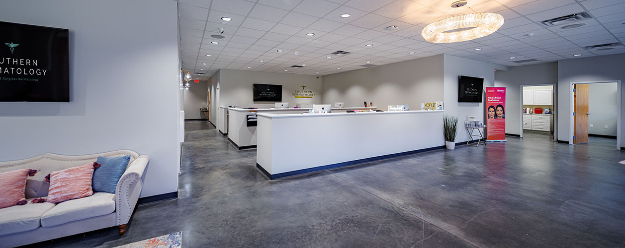 The Evans, GA reception area at Southern Dermatology — open lobby, polished concrete floor, navy-background wall screens.